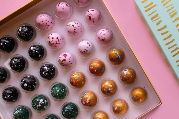 Colourful chocolate truffles in a box on a pink surface