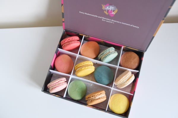 box of pastel-coloured macarons on a white surface