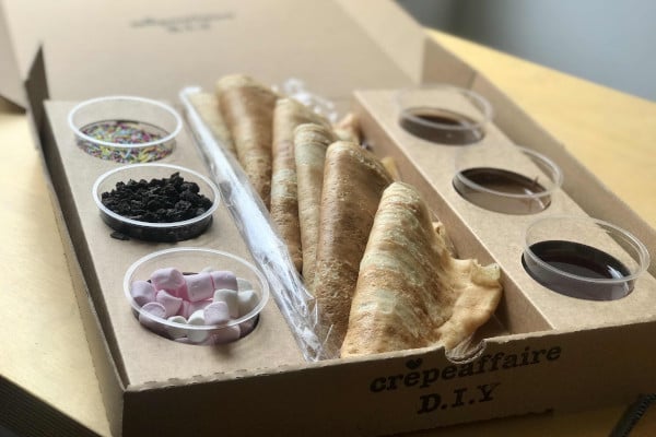 cardboard box full of crepes and toppings