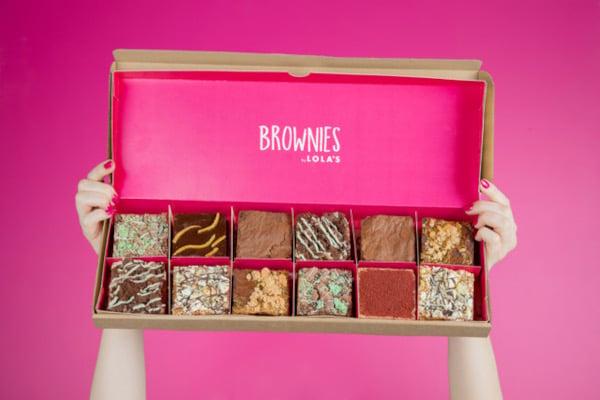 Hands holding up pink box of brownies
